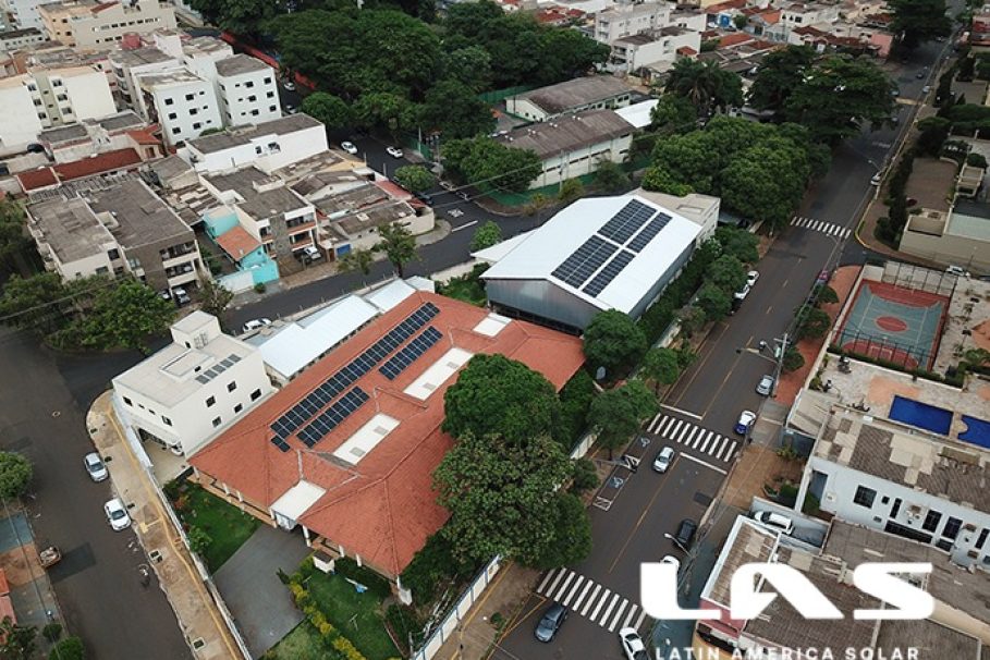 Vista aérea de um bairro urbano com prédios e casas, destacando construções com painéis solares nos telhados.